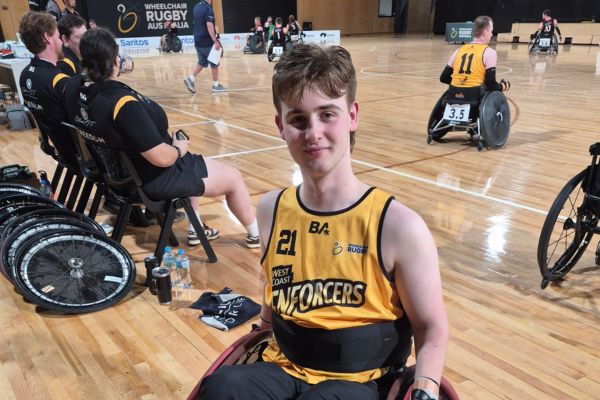A teenager in a wheelchair on a wheelchair rugby court